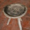 A wooden stool sitting on top of a brick floor
