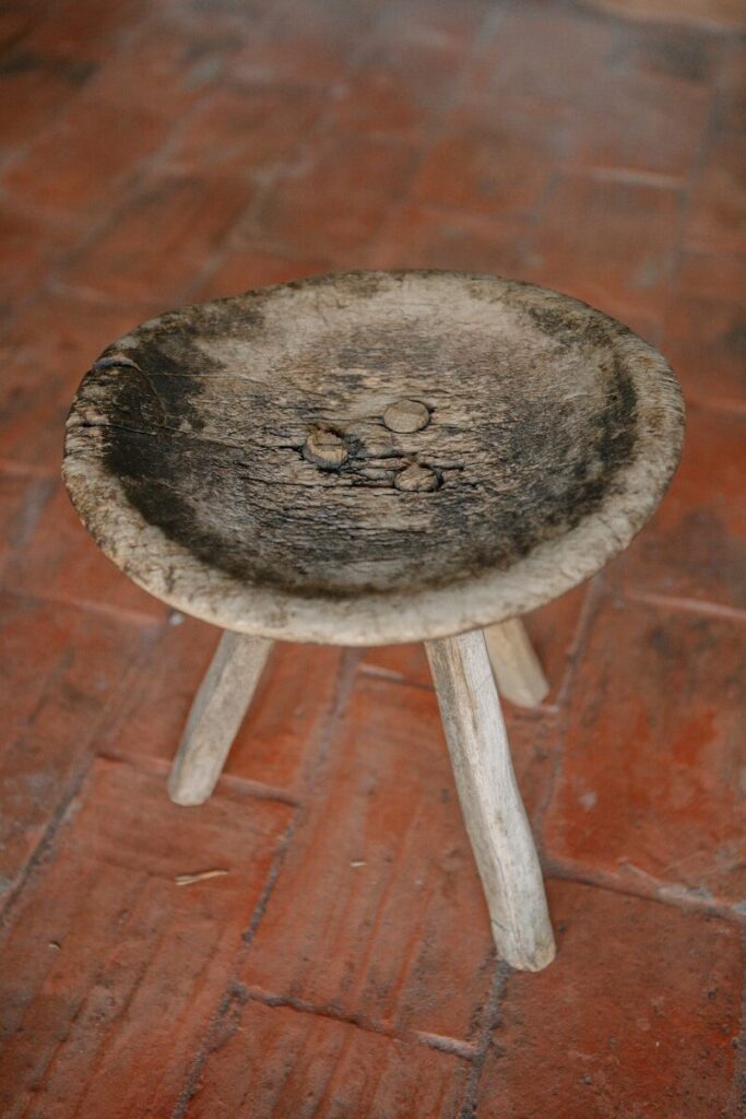 A wooden stool sitting on top of a brick floor